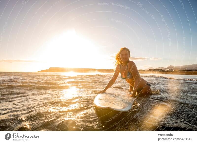 Spain, Tenerife, young female surfer at sunset sunsets sundown surfing surf ride surf riding Surfboarding woman females women surfers female surfers evening