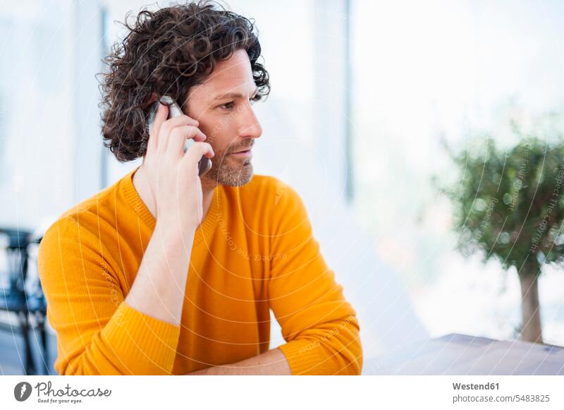 Man with curly brown hair telephoning with smartphone man men males on the phone call On The Telephone calling Smartphone iPhone Smartphones Adults grown-ups
