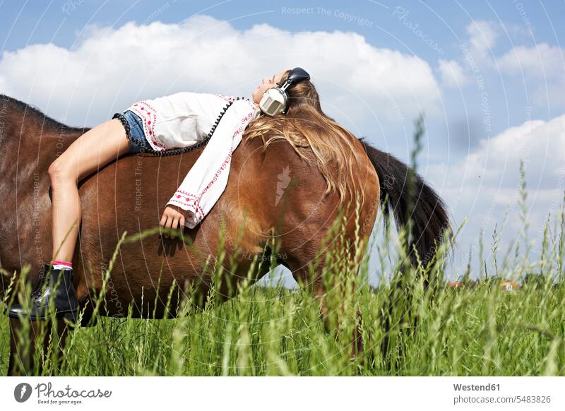 Girl with headphones lying on horseback equus caballus horses girl females girls riding horse riding ride headset mammal mammalian mammals mammalians animal