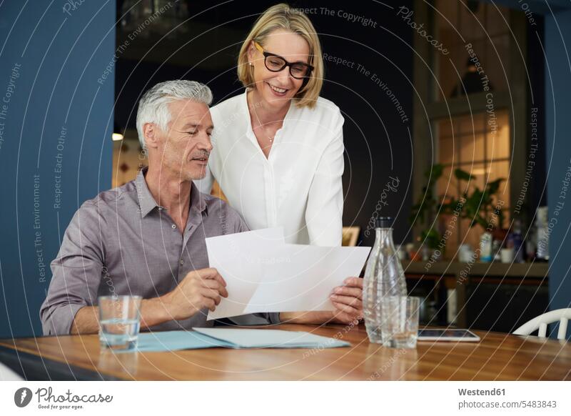 Mature couple with documents at home smiling smile twosomes partnership couples people persons human being humans human beings flat flats apartment apartments