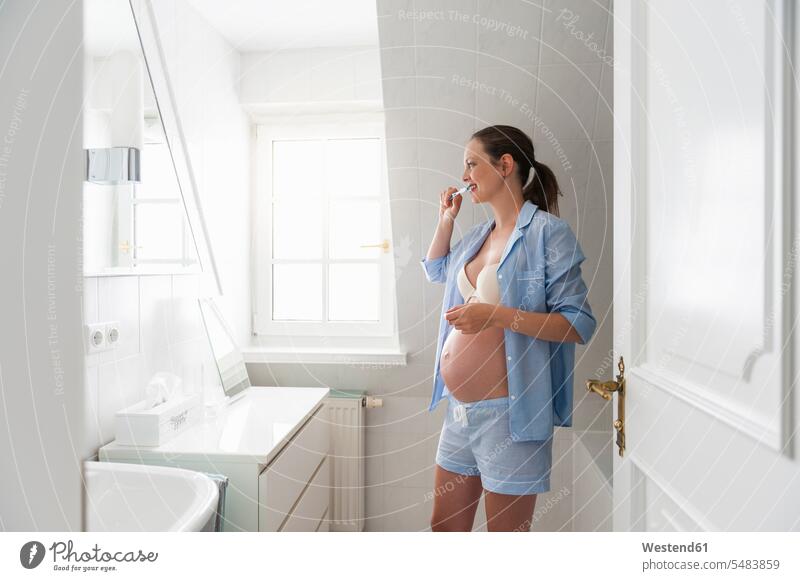 Pregnant woman in bathroom brushing her teeth females women brushing teeth pregnant Pregnant Woman Adults grown-ups grownups adult people persons human being