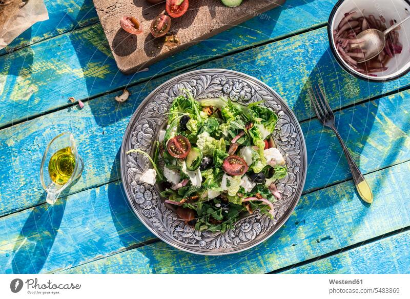 Greek salad with arugula, cheece, olives, tomatoes, cucumber, onion and caramelized nuts Plate dish dishes Plates wood wooden healthy eating nutrition