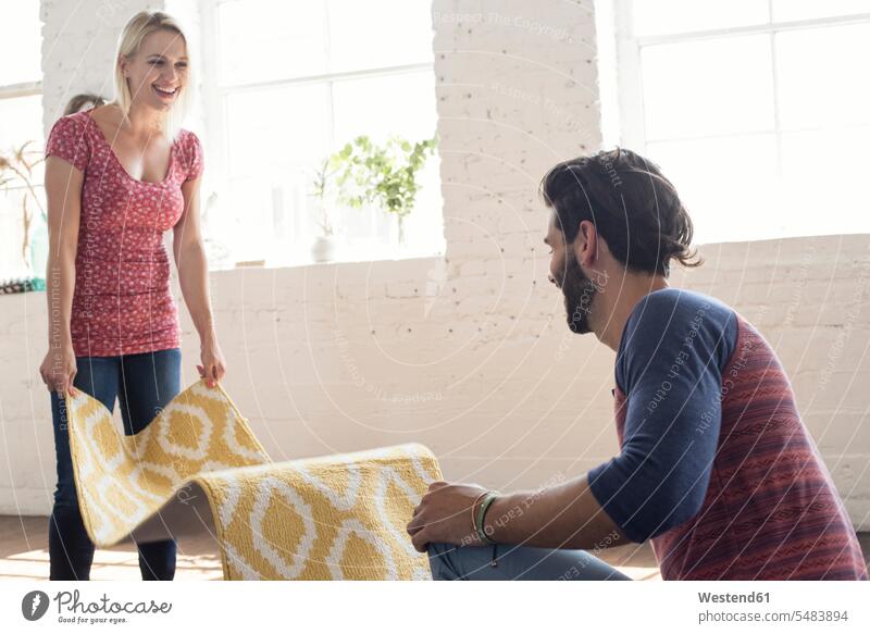Young couple placing carpet in a loft carpets rug rugs twosomes partnership couples people persons human being humans human beings lofts USA United States