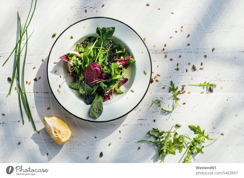 Spring salad of baby spinach, herbs, arugula and lettuce on plate, lemon Plate dish dishes Plates wood wooden Preparation prepare preparing healthy eating