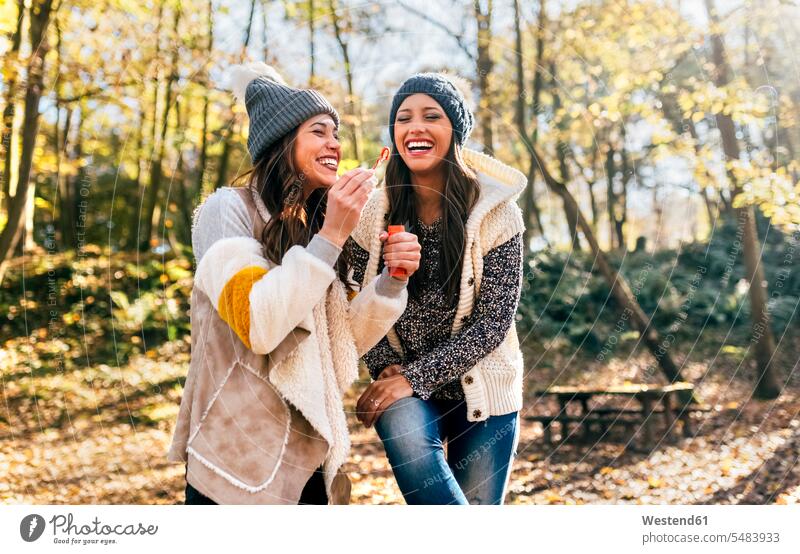 Two beautiful women having fun with soap bubbles in an autumnal forest female friends Fun funny fall woods forests woman females mate friendship Adults