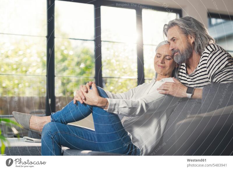 Happy senior couple sitting at home senior adults seniors old together couch settee sofa sofas couches settees happiness happy Seated twosomes partnership