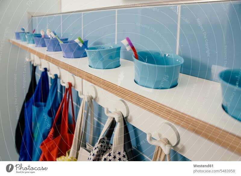 Line-up of of toothbrushes and bags on hooks in kindergarten in a row Rows nursery school toothbrush mug pedagogics daycare centre daycare center Dental Health