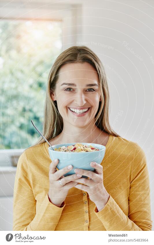 Portrait of happy woman holding bowl with muesli females women smiling smile Granola Muesli cereals portrait portraits happiness eating Adults grown-ups