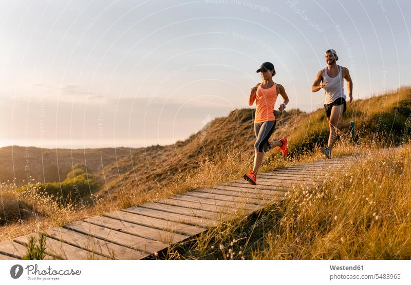 Spain, Aviles, athletes couple running along a coastal path at sunset twosomes partnership couples runner runners leisure free time leisure time Jogging jogger