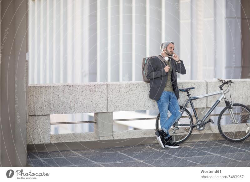 Young man on cell phone next to bicycle mobile phone mobiles mobile phones Cellphone cell phones men males on the phone call telephoning On The Telephone
