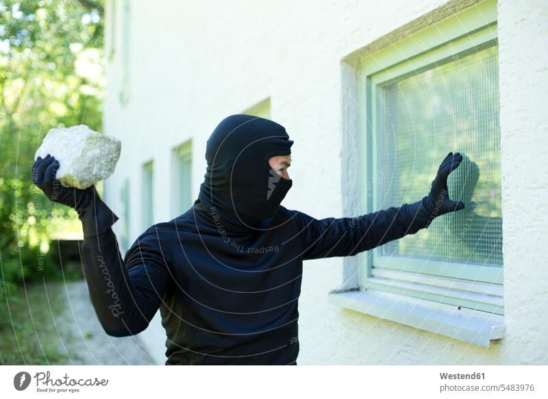Burglar with stone breaking window man men males burglar housebreakers burglars burglary housebreaking windows Adults grown-ups grownups adult people persons