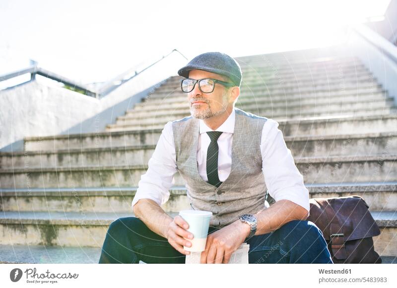 Businessman with coffee and newspaper in the city sitting on stairs break Business man Businessmen Business men stairway Coffee business people businesspeople