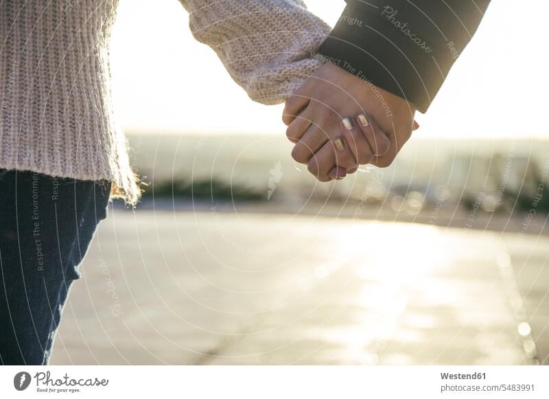 Young couple holding hands at backlight, close-up Korean Ethnicity focus on foreground Focus In The Foreground focus on the foreground Part Of partial view