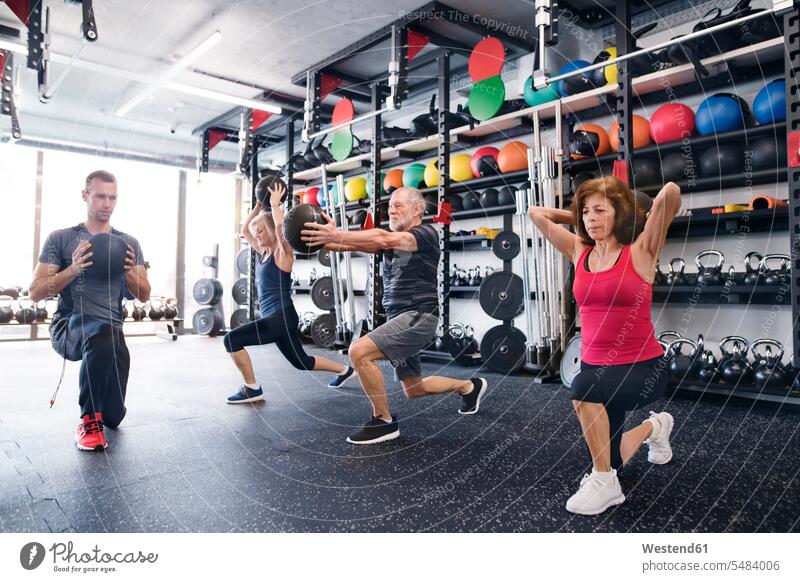 Group of fit seniors with personal trainer in gym exercising with medicine balls exercise training practising senior adults old gyms Health Club Adults