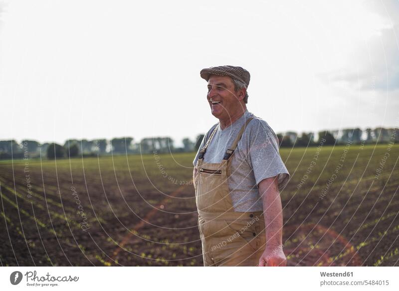 Smiling farmer standing at a field smiling smile agriculturists farmers Field Fields farmland agriculture man men males Adults grown-ups grownups adult people
