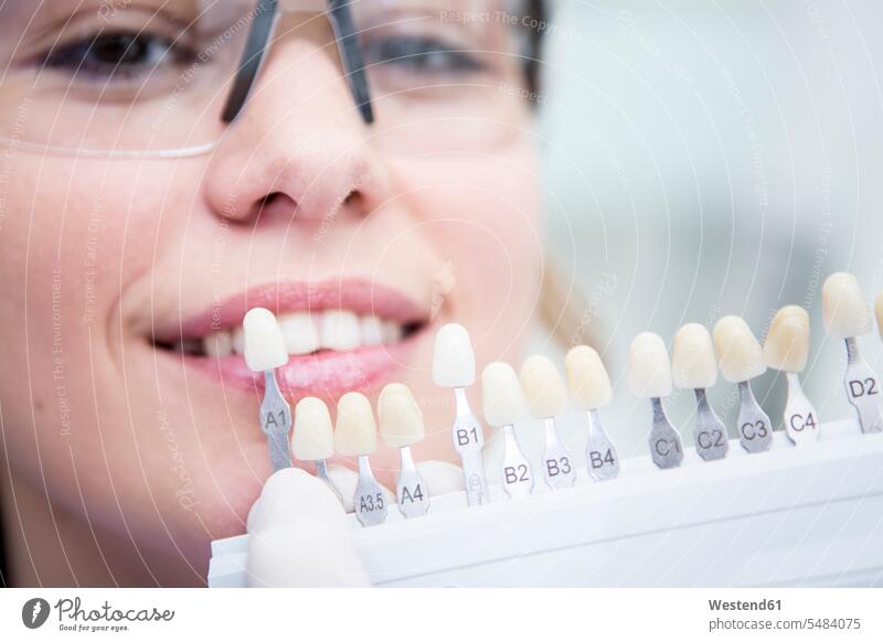 Woman at the dentist choosing color for teeth whitening smiling smile tooth woman females women dental surgery people persons human being humans human beings