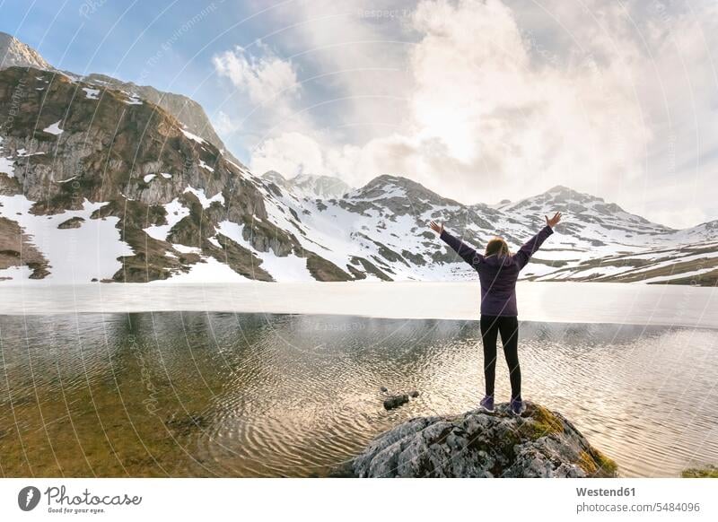 Spain, Asturias, Somiedo, woman standing with raised arms at mountain lake hiker wanderers hikers females women happiness happy hiking Adults grown-ups grownups
