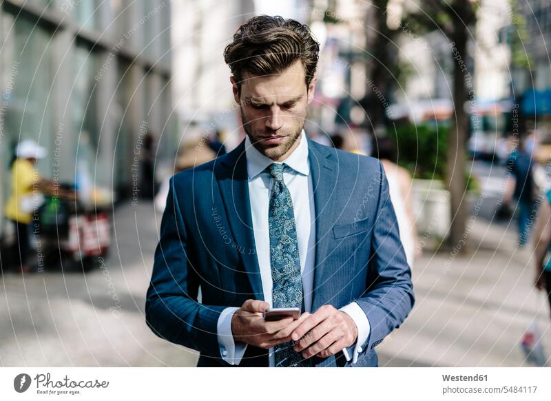 Handsome businessman walking in Manhattan, using mobile phone attractive beautiful pretty good-looking Attractiveness commuter commuters reading going mobiles