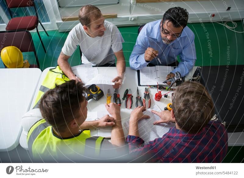 Electrician instructor sitting with students at table Person in Education apprenticeship teacher teachers learning teaching pedagogue pedagogues education