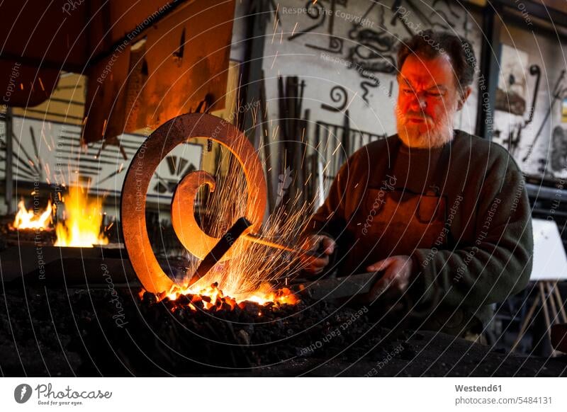 Blacksmith at work in his workshop blacksmith working At Work craftsman trade craftsmen Craft Occupation Manual Workers manual laborour handworker Tradesman