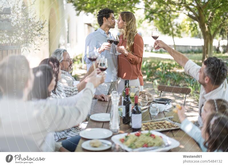 Couple kissing during lunch in garden with red wine Red Wine Red Wines group of people Group groups of people celebrating celebrate partying kisses family