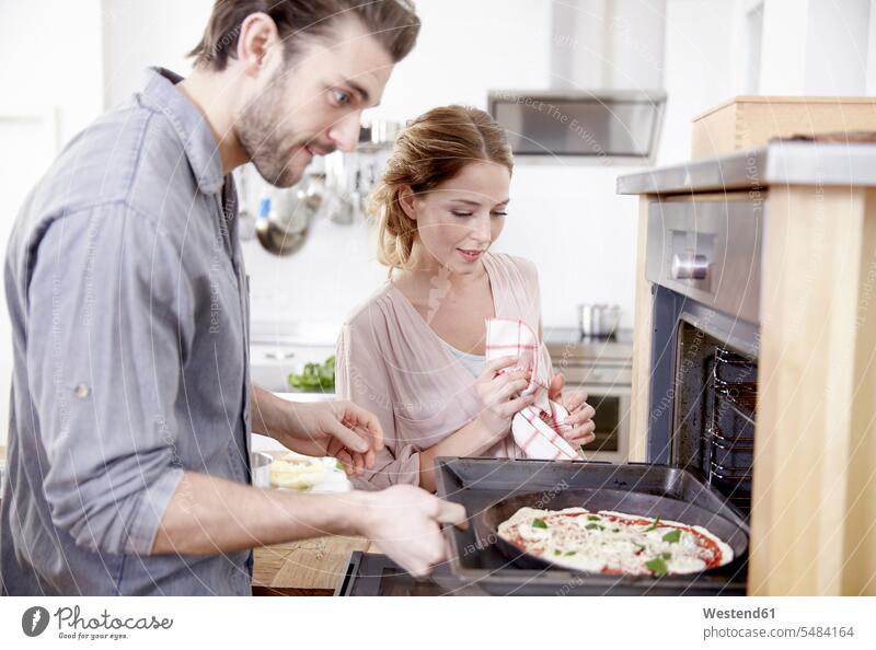 Couple putting pizza into oven caucasian caucasian ethnicity caucasian appearance european preparing Food Preparation preparing food two people 2 2 persons