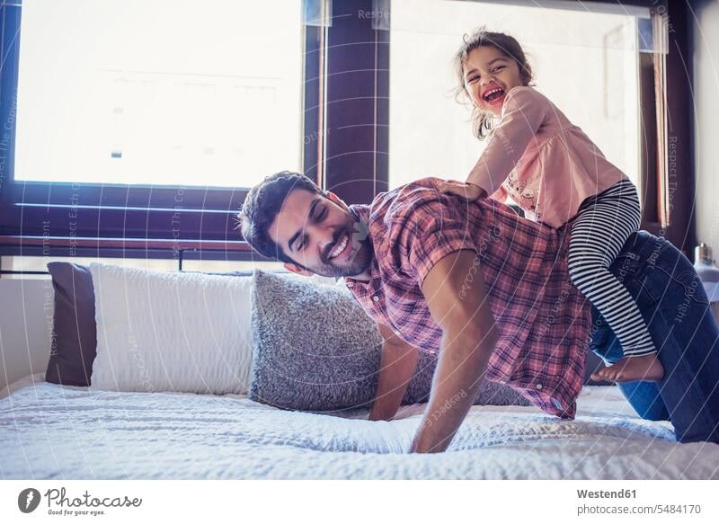 Father and daughter playing on bed father pa fathers daddy dads papa together daughters riding ride beds parents family families people persons human being