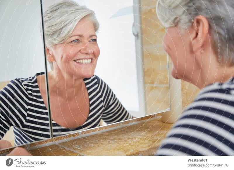 Portrait of smiling woman watching herself in bathroom mirror mirrors females women Adults grown-ups grownups adult people persons human being humans