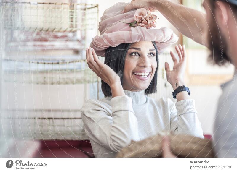 Portrait of woman putting on an old hat in antique shop beautiful shopping spree shopping expedition selection Assortment face to face Facing Each Other