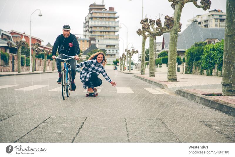 Happy couple with bicycle and skateboard on the street Skate Board skateboards bikes bicycles riding road streets roads twosomes partnership couples