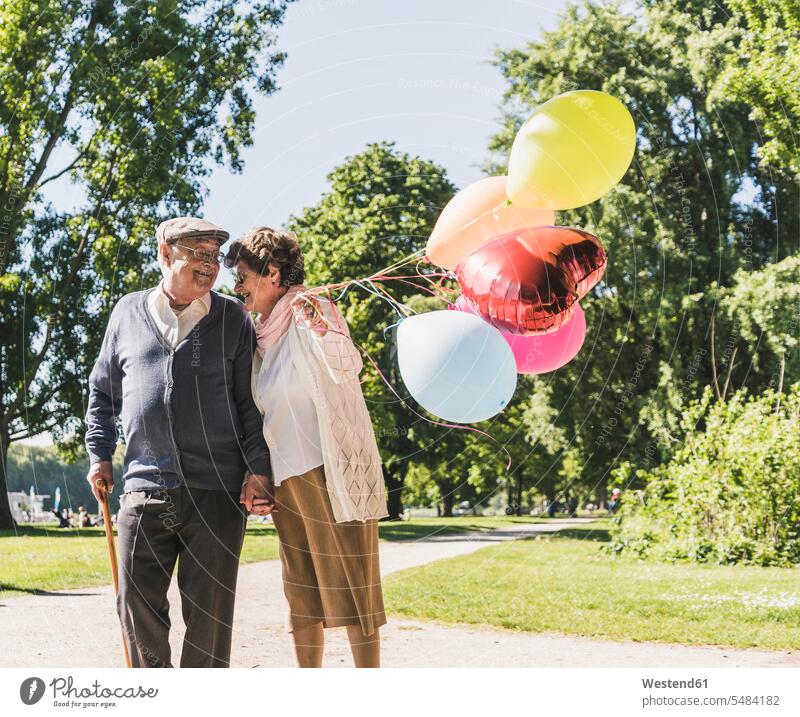 Happy senior couple with balloons in a park elder couples senior couples adult couple adult couples twosomes partnership people persons human being humans