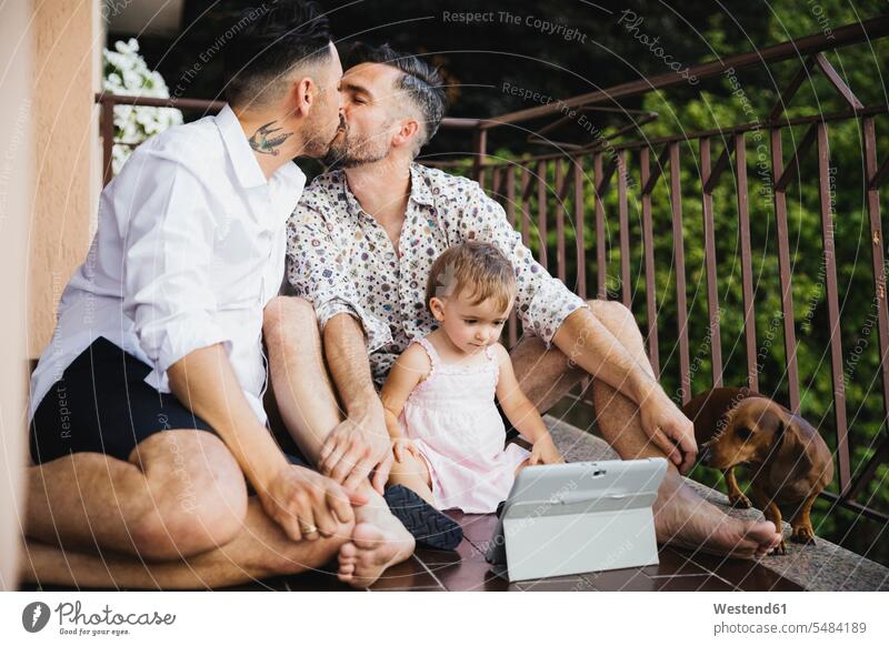 Gay couple kissing with daughter and dog on balcony gay gay men gay man homosexual men homosexual man kisses tablet digitizer Tablet Computer Tablet PC