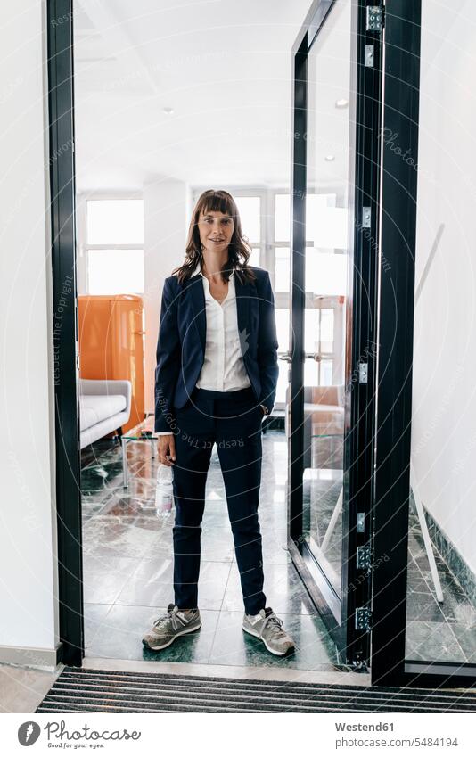 Businesswoman wearing trainers, standing in open door businesswoman businesswomen business woman business women runners running shoe running shoes amiable