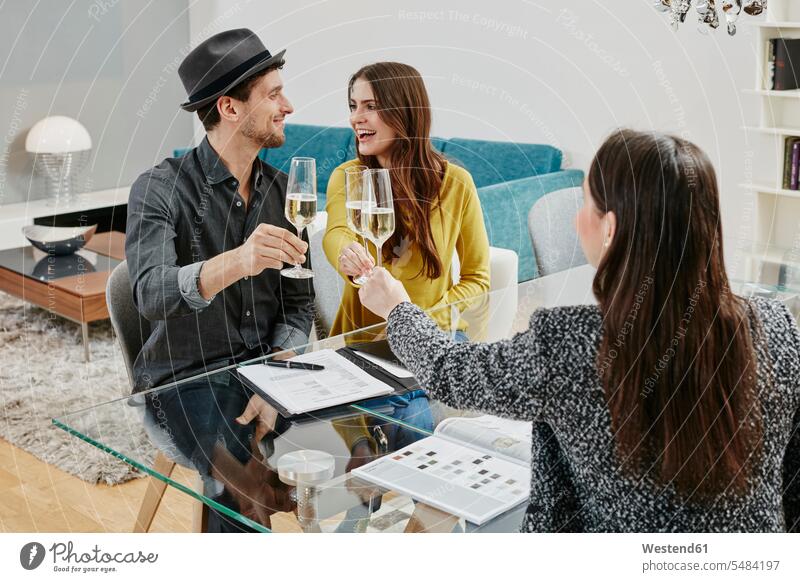 Couple celebrating sales contract in furniture store Furniture Furnitures toasting clinking cheers couple twosomes partnership couples shopping celebrate