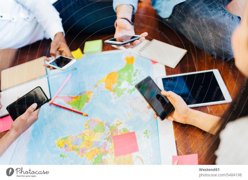 Group of friends with smartphones planning vacation together map maps travelling traveling mobile phone mobiles mobile phones Cellphone cell phone cell phones