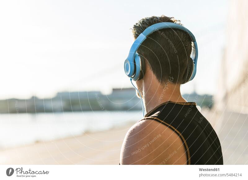 Young man with headphones looking at distance jogger joggers men males athlete Sportspeople Sportsman Sportsperson athletes Sportsmen fit sportive sporting