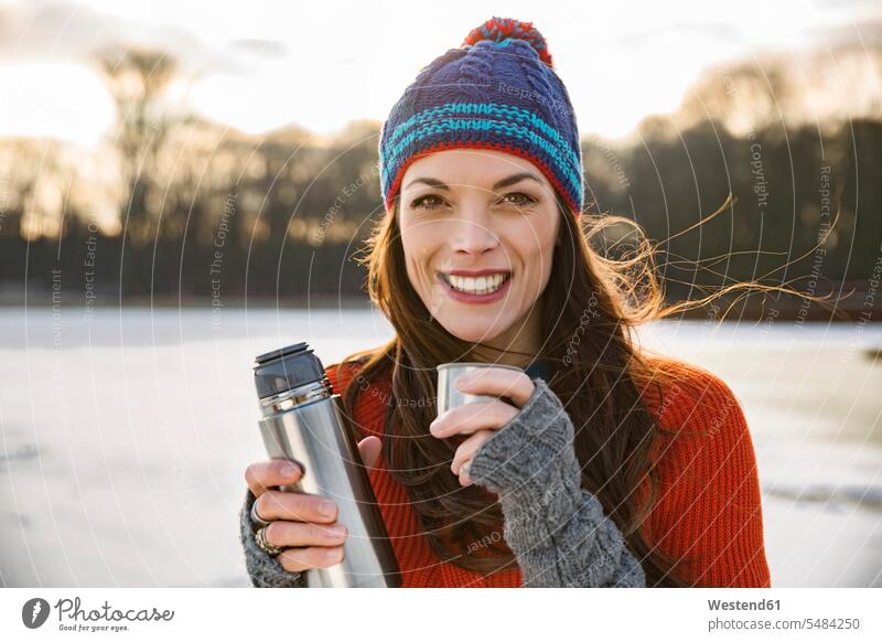 Portrait of smiling woman drinking hot beverage from thermos flask outdoors in winter woolly hat Wooly Hat Knit-Hat Knit Hats wool cap smile females women hats