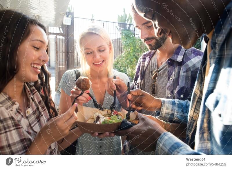 Happy friends sharing takeaway food outdoors share Snack Snacks Snack Food smiling smile eating friendship Meals foods food and drink Nutrition Alimentation