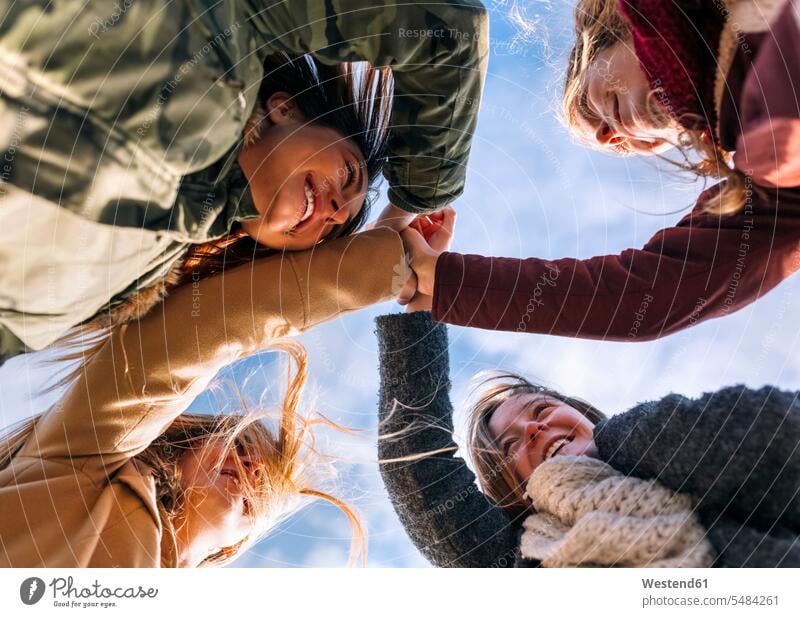 Four happy friends huddling outside mate female friend hand in hand holding hand stand human human being human beings humans person persons caucasian appearance