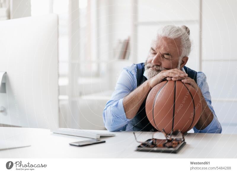 Relaxed mature man on at desk with basketball Basketball portrait portraits sleeping asleep relaxed relaxation men males sport sports relaxing Adults grown-ups