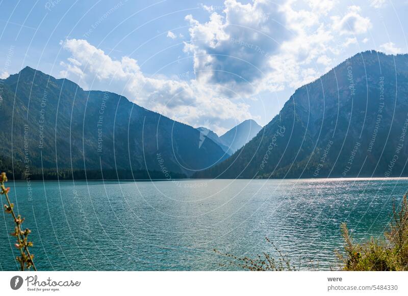 Evening sun rays through clouds on blue sky over Plansee lake in Austria Swim Water Water sports Waves Wet alps copy space evening landscape mountain backdrop