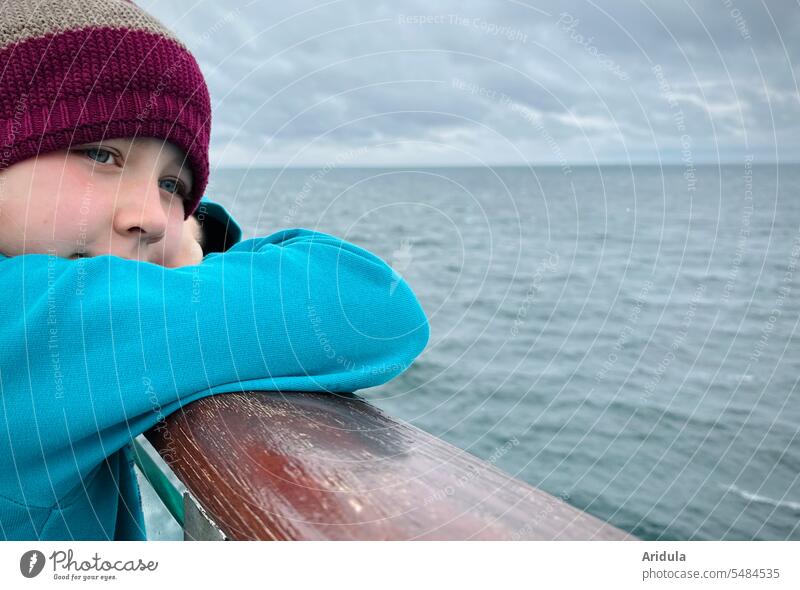 Child standing at the railing of a ferry looking out to the gray Baltic Sea Railing Girl Ferry Ocean View into the distance Navigation ship voyage