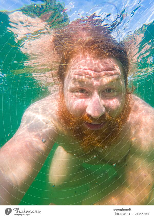 Man with red hair and red beard diving in a freshwater lake. Eyes open. Lake underwater Dive be afloat bathe reflection Red-haired Diver Summer