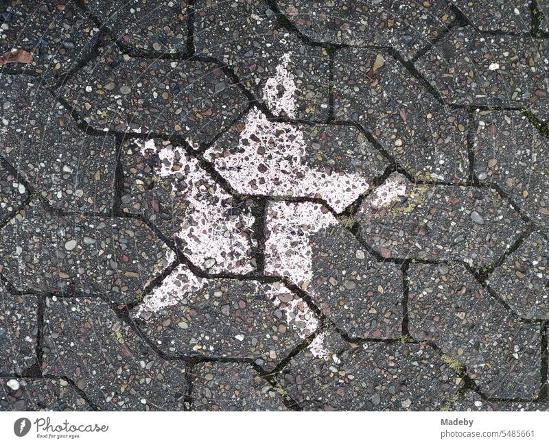 White faded painted star on the gray composite pavement of a schoolyard after a graduation ceremony at Niklas Luhmann Gymnasium in Oerlinghausen near Bielefeld in the Teutoburg Forest in East Westphalia-Lippe, Germany