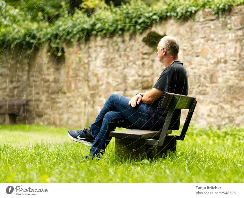 Middle-aged man sits on a park bench with averted gaze into the distance Man Only one man middle-aged man Mature man Mid adult man mature adult 50 - 55 years