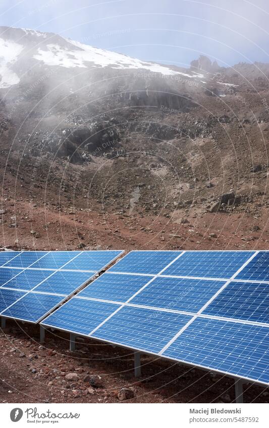 Solar panels with Chimborazo volcano in background, selective focus, Ecuador. solar panel sunlight electricity photovoltaic PV nature mountain cell