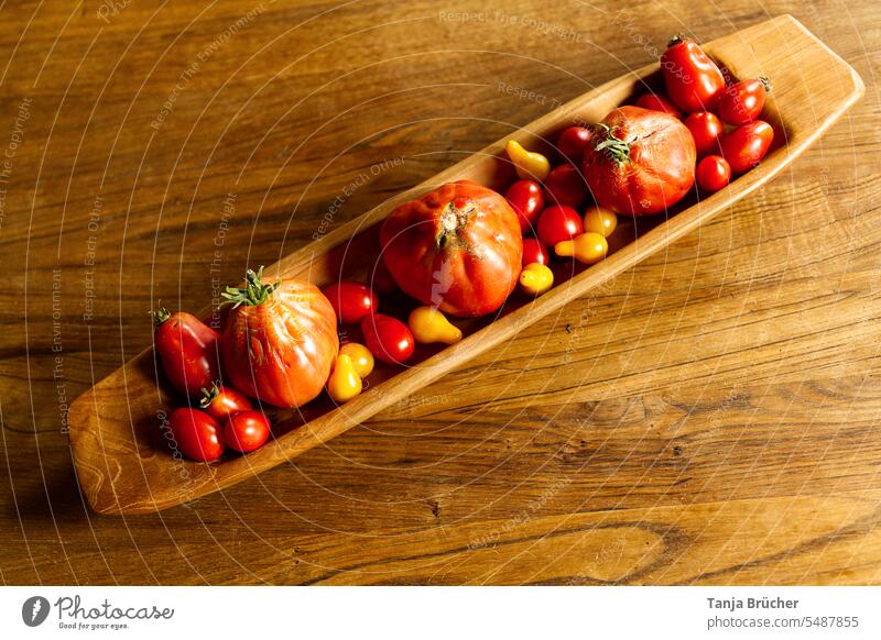 Red and yellow tomatoes from above in oblong wooden bowl on grained wooden table Vegetable red tomatoes Tomato from on high many tomatoes freshly harvested