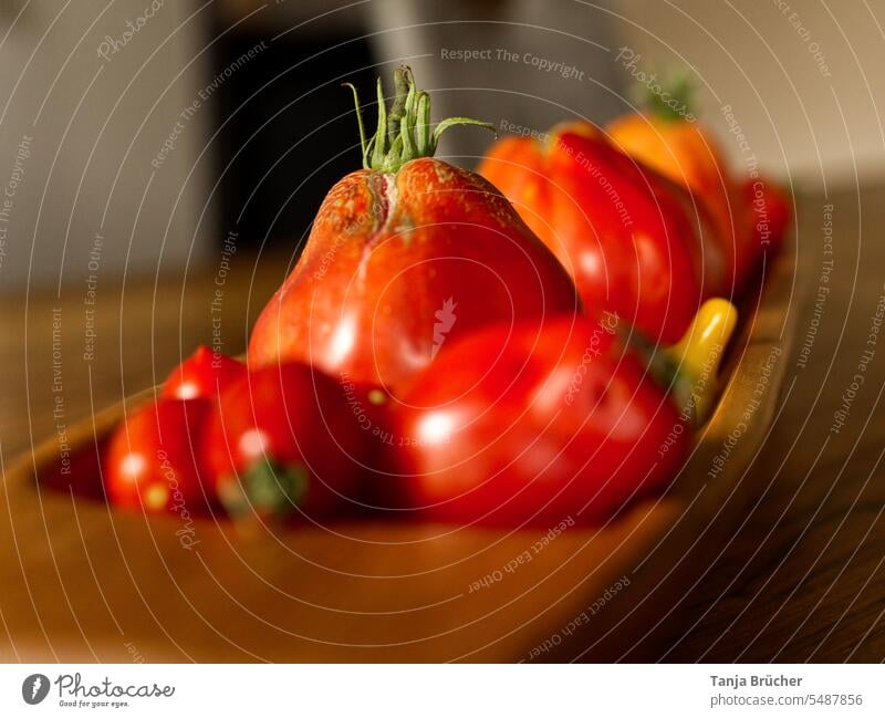 Close-up of tomatoes in an elongated wooden bowl Organic vegetables Vegetable Tomato red tomatoes yellow tomatoes Vegan diet fresh harvest many tomatoes