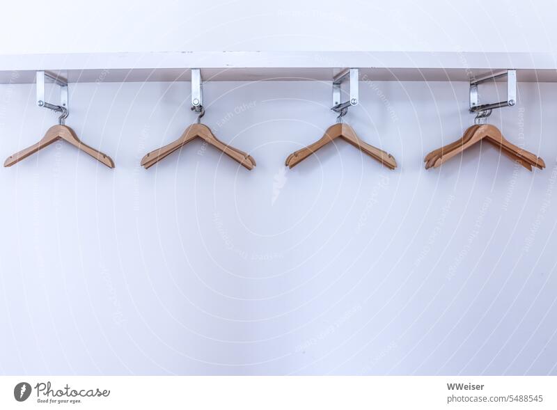 Several empty wooden hangers hang on the plain wardrobe in front of a white wall Hanger Empty Attract move out Clothing Jacket Coat Arrangement arrange Hang up