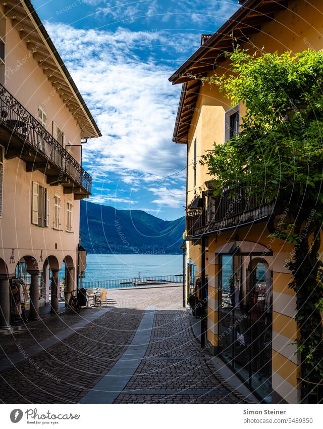 View of Lake Maggiore through a street Lago Maggiore Street houses Town Water Exterior shot Mountain Landscape